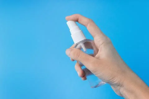 A woman's hand with an antiseptic on a blue background close-up. Stock Photos