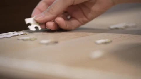 Woman’s Hand Assembling Jigsaw Puzzle Pieces on Wooden Table 動画素材 337083937
