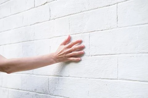 Woman's hand on the background of a white brick wall Stock Photos