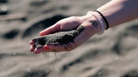 Woman's hand with black volcanic sand on the beach of mediterranean sea in Rome Stock Footage 117682002