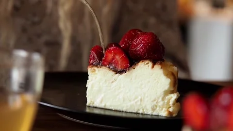 Woman's hand breaks off piece of cheesecake with  strawberries with a fork Stock Footage 200071518