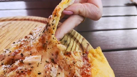 Woman's hand breaks slice of hot, fragrant pizza lying on wooden tray. Unhurr Stock Footage 208951481