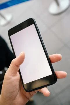 Woman's hand browsing mobile phone in a queue line Stock Photos