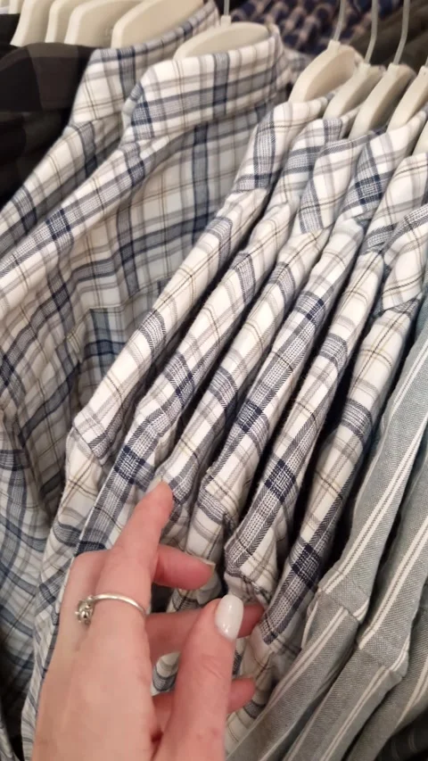 Womans Hand Browsing Plaid and Striped Shirts on Clothing Rack Stock Footage 326061090