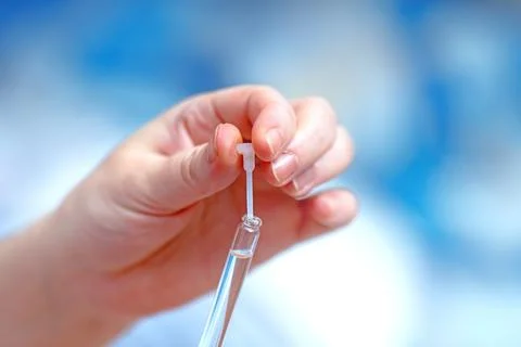 Woman's hand carefully removing a precision plastic pipette from a test tub.. Fotos Stock