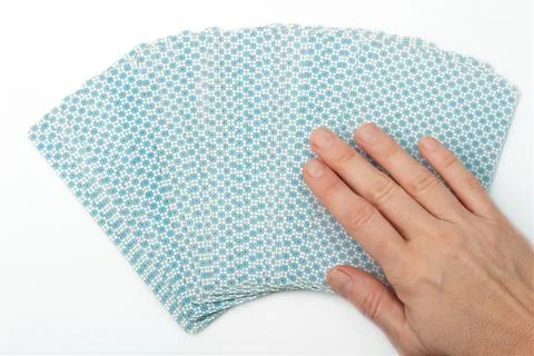 Woman's hand choosing a play card over a white surface from above view Stock Photos