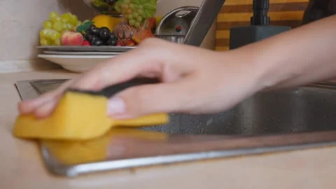 Woman's hand cleaning kitchen sink rim with sponge Stock Footage 323949252