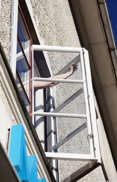 A woman's hand cleans windows on the second floor Stock Photos