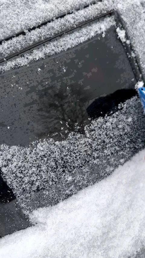 A womans hand clears snow from a car window with a scraper. Stock Footage 327072783
