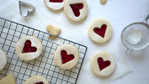 Womans hand comes into shot and takes a bite from a heart shaped biscuit Stock Footage