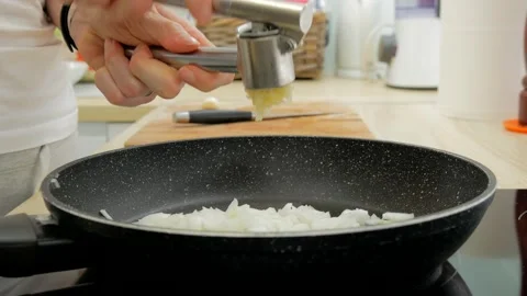 Woman's hand crushing garlic using a garlic press. Stock Footage 136388966