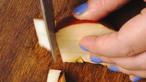 A woman's hand cuts apples into cubes with a knife on a wooden board. Stock Footage 168988015
