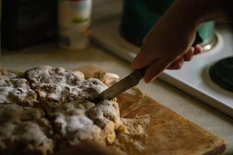 A woman's hand cuts a ready-made Charlotte apple pie with a knife in the kitchen Stock Photos