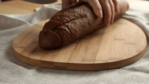 Woman's hand cuts a rye loaf with a knife on a wooden board Stock Footage 170131264