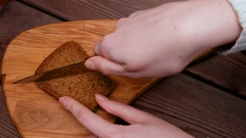 A woman's hand cuts a slice of bread in half on a board. breakfast sandwich Stock-Footage 150836466