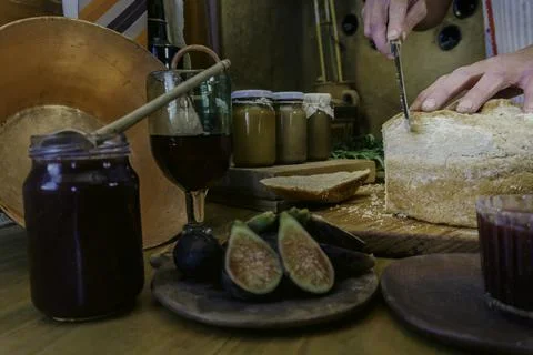 Woman's hand cutting bread to spread jam Stock Photos