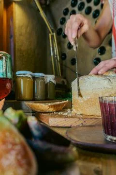 Woman's hand cutting bread to spread jam Stock Photos