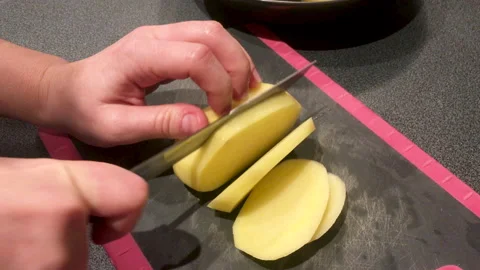 Woman's hand cutting potatoes on a cutting board Stock Footage 164654633