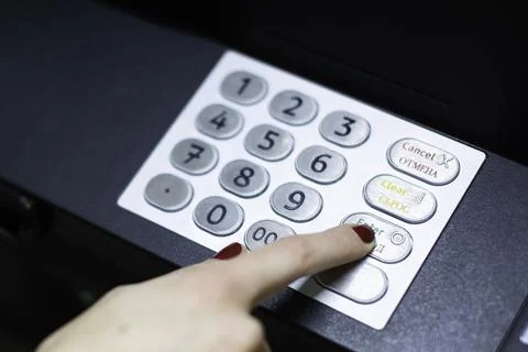 A woman's hand dials a pin code on an ATM Foto stock