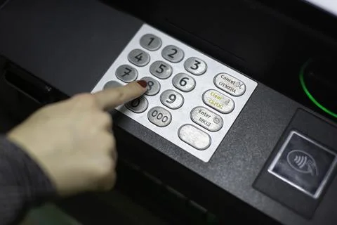 A woman's hand dials a pin code on an ATM Fotos de archivo