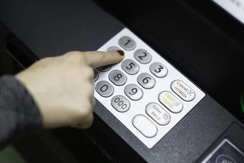 A woman's hand dials a pin code on an ATM Фото