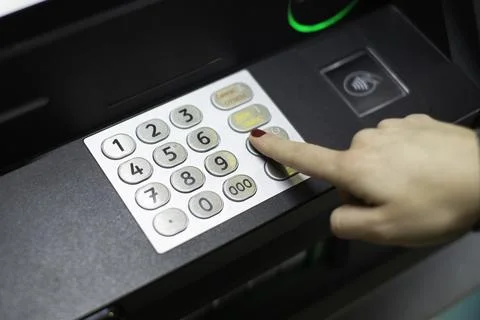 A woman's hand dials a pin code on an ATM Stock Photos