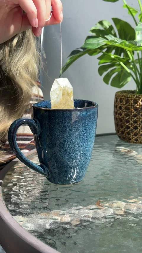 Woman's hand dipping a tea bag in a blue ceramic mug for a relaxing morning.. Stock Footage 331883903