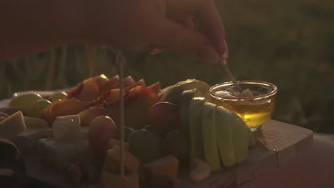 A woman's hand dips the cheese on a stick into the honey, Stock Footage 153862044
