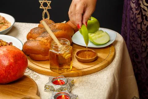 A woman's hand dips a piece of apple in honey in honor of the celebration of  Stock Photos
