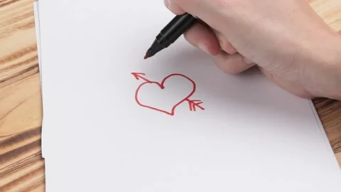 A woman's hand draws a heart on paper with a red marker. Stock Footage 167182953