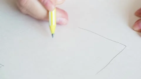 Woman's hand draws an image of a house on a sheet of white paper Stock Footage 169753579