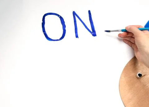A woman's hand draws on a large sheet of paper blue letters he, space for a copy Stock Photos