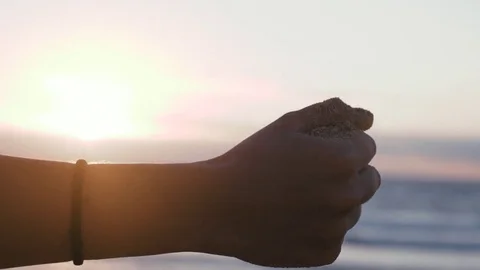 Womans hand dropping sand at beach during sunset Stock Footage 71554151