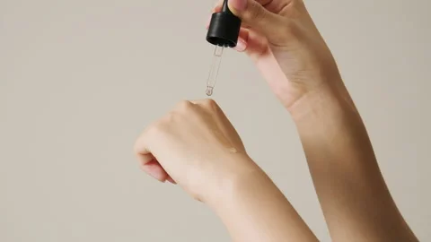 A woman's hand dropping a transparent ampoule onto the back of her hand. 스톡 동영상 252641687