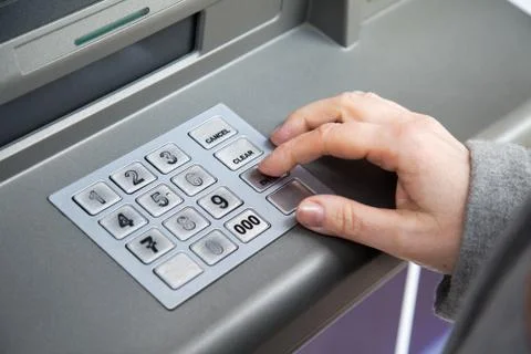 Woman's hand enters the pin code into ATM Stock Photos