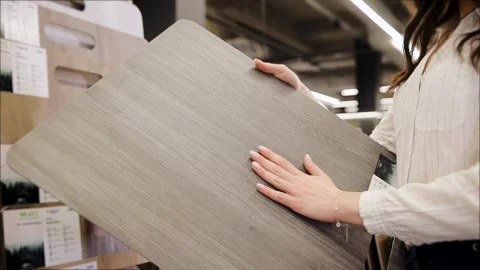 Woman's hand examines a laminate floor in a hardware store. Parquet panel sample Stock Footage 265899040