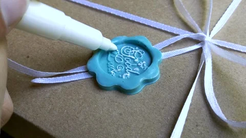 A woman's hand with a felt-tip pen is coloring a wax seal Stock Footage 296192184