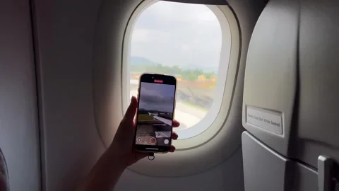 A womans hand films the road through an airplane window Phone airplane window Stock Footage 316048090