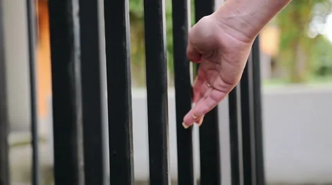  woman's hand gently touch the iron bars of a building Stock Footage 67818400