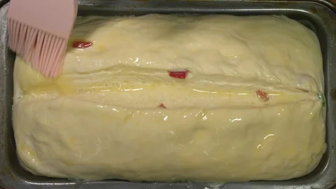 A woman’s hand glazing the top of a bread loaf, prior to baking. Stock Footage 255506240