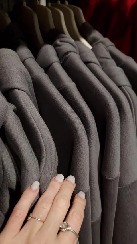 Womans Hand Gliding Over Gray Hoodies on a Retail Rack Stock Footage 326061567