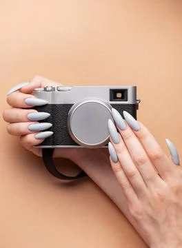 Woman's hand with grey nail polish holding camera Stock Photos