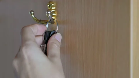 A woman's hand hangs a bunch of keys on a cabinet hook in the hallway. Video stock 211139761