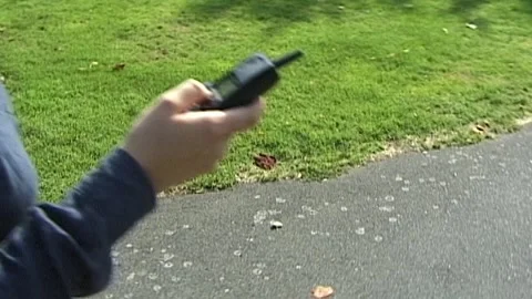 Woman's hand holding 90's brick phone in park Stock Footage 244841866