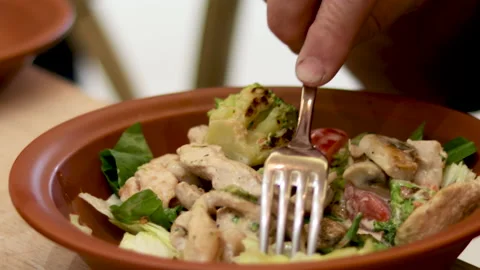 Woman's hand holding fork and eating hot salad in a restaurant Stock Footage 169998968
