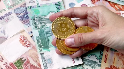 Woman's hand holding a heap of Bitcoin coins above Russian banknotes Stock Footage 281293427