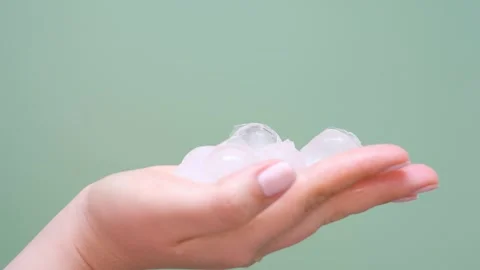 A woman's hand holding ice balls on a green background close-up. Vídeos de archivo 346110974