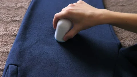 Womans hand, holding a machine for removing pellet and pools from clothes and Stock Footage 213273564