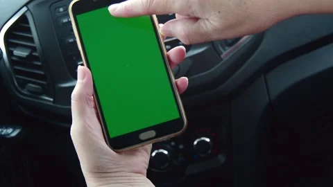 Woman's hand holding a mobile phone with a vertical green screen in a car Stock Footage 172064915