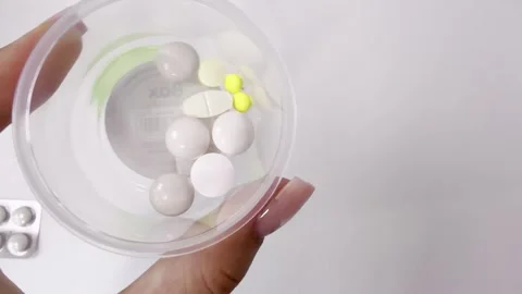 Woman's hand holding a plastic cup with various pills, tablets, and supplem.. Vídeos de archivo 335141529
